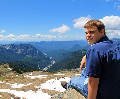 Wesley sitting at Mount Rainier looking over shoulder back to the camera.